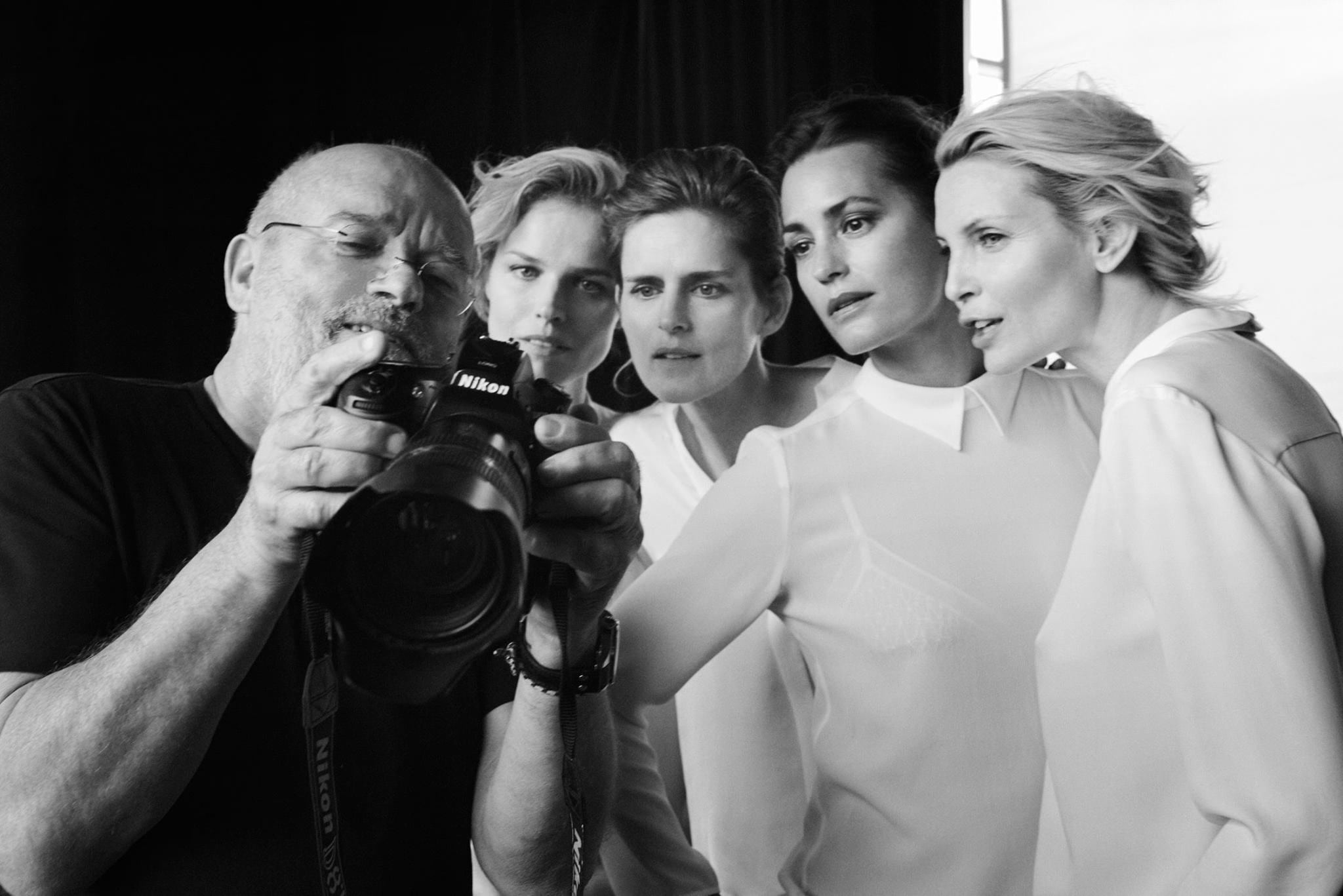 A photographer shows images on his camera screen to four women gathered around him