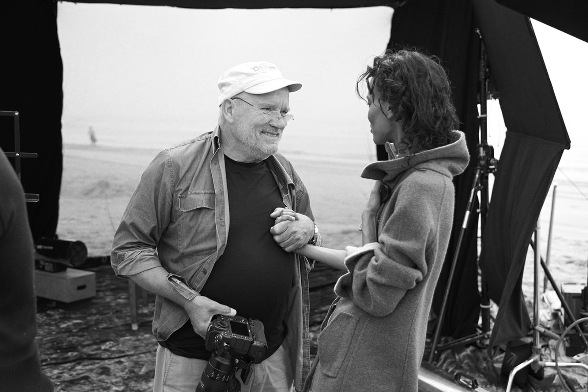 Peter Lindbergh holding hands and smiling with a woman on a photoshoot set